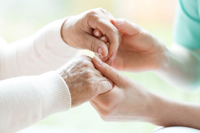 Young hands hold a pair of elderly hands.