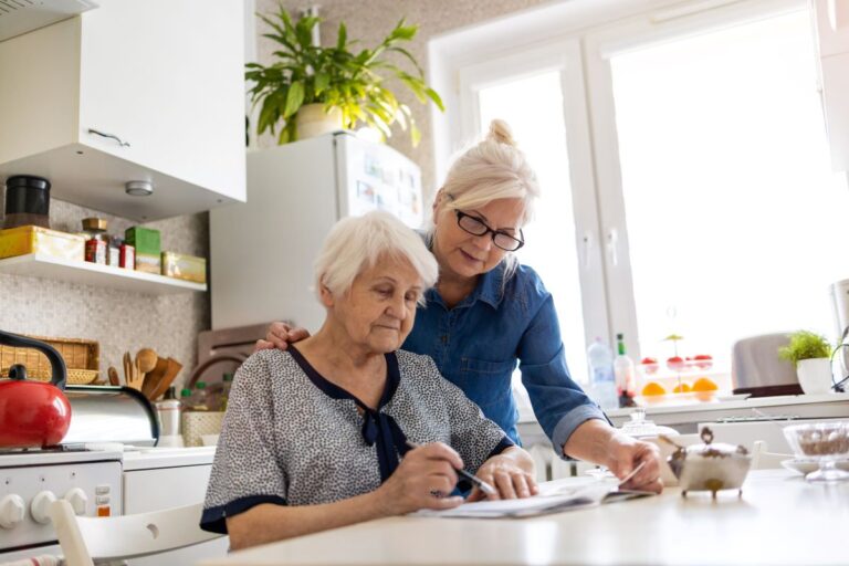 A support worker helps an elderly woman with paperwork.